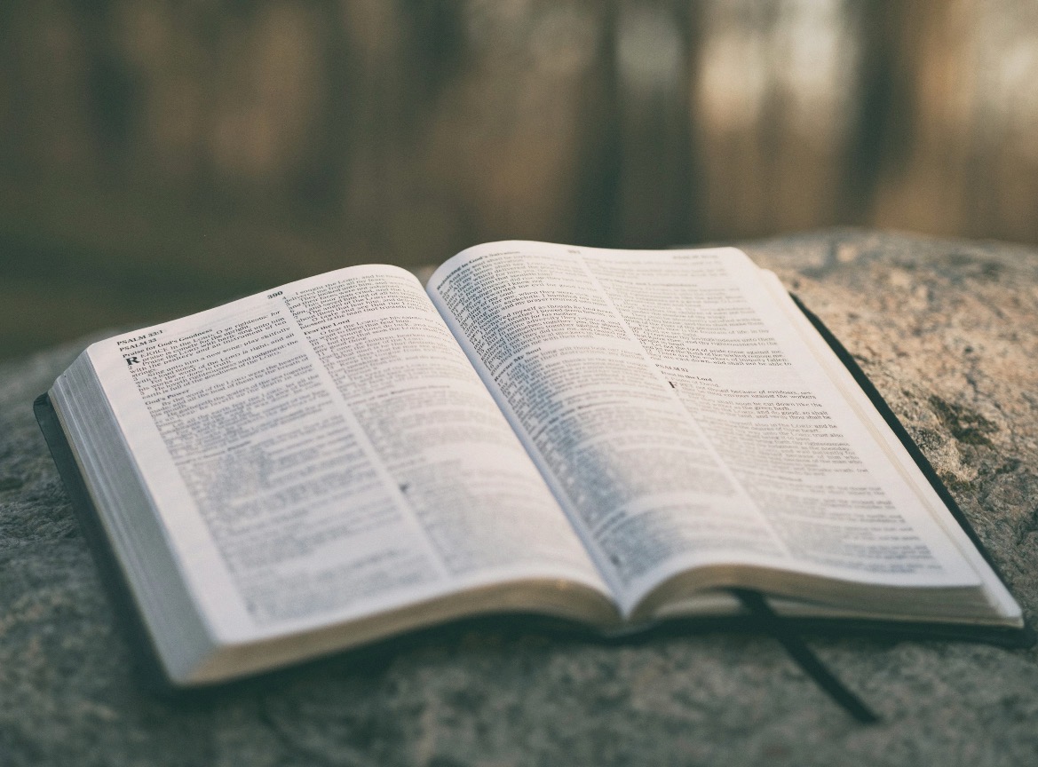 An open Bible resting on a stone surface